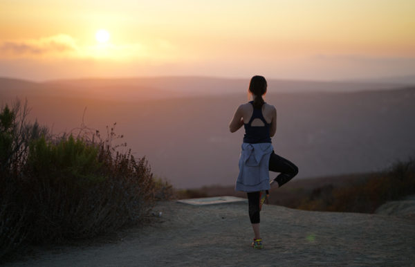 woman enjoying yoga a sunset - contact Yoga Oasis.